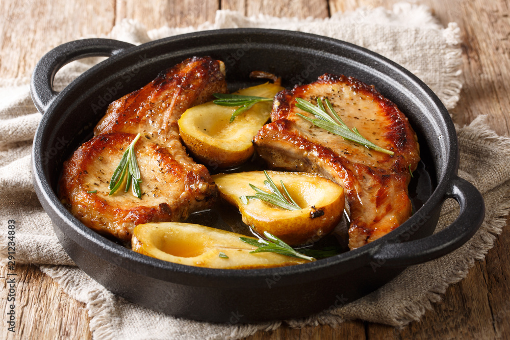 Hot spicy baked pork chops with pears and rosemary in honey-garlic sauce served in a pan close-up. horizontal