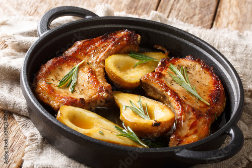 Rustic style baked pork chops with pears and rosemary in honey-garlic sauce served in a pan close-up. horizontal