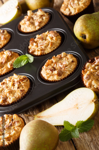 pear muffin with cinnamon and walnuts in a baking dish close-up. vertical