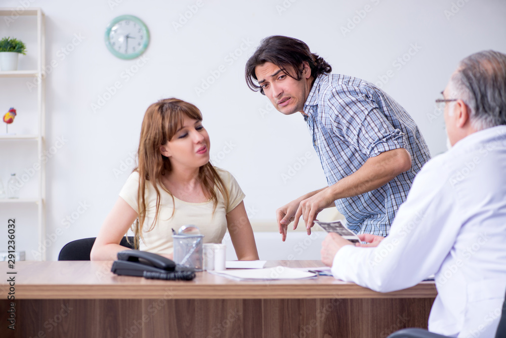 Young couple visiting old male doctor Young couple visiting old male doctor