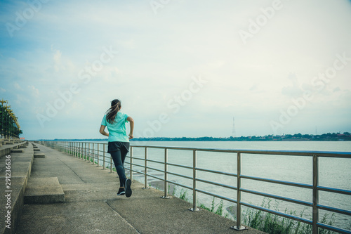 Young woman running on the street with a view of the river in the morning.