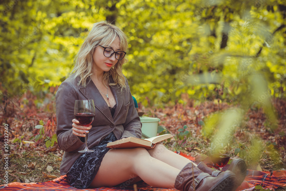 Autumn scene with middle aged plus size woman, glass of wine, fruits and book Autumn scene with middle aged plus size woman, glass of wine, fruits and book