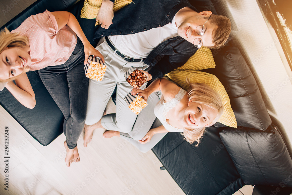 Fototapeta premium Cheerful group of friends eating popcorn at home