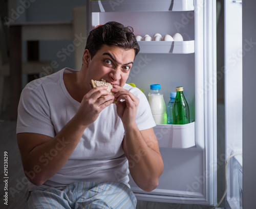 Man at the fridge eating at night Fototapeta