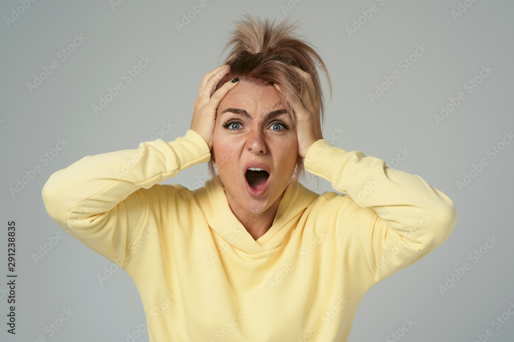 Close up of young attractive caucasian woman in yellow hoodies looking at camera posing funny, shocked with expression. Positive emotions of girl. Model tests on white background Close up of young attractive caucasian woman in yellow hoodies looking at camera posing funny, shocked with expression. Positive emotions of girl. Model tests on white background