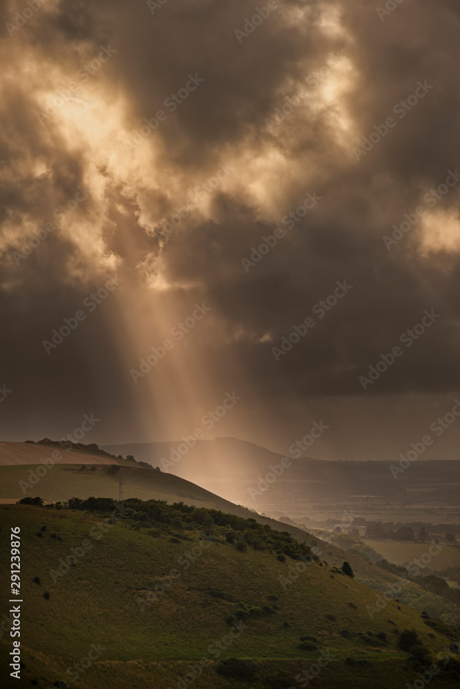 Stunning Summer landscape image of escarpment with dramatic storm clouds and sun beams streaming down