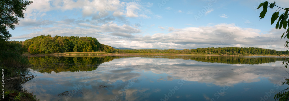 Beautiful panorama of autumn lake against the background of forest and sunny sky