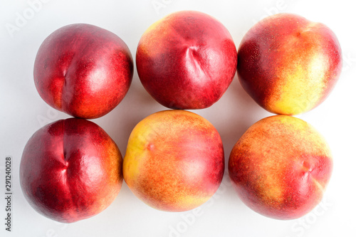 Six fresh ripe nectarine fruits displated as on two lines on a white table  isolated on white  with soft focus  top view
