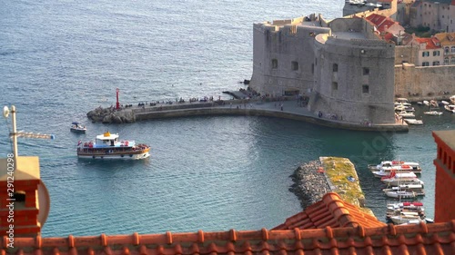 A pleasure ship with tourists approaches the fortress of a medieval city