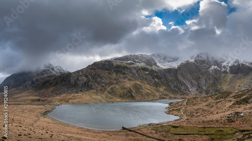 Beautiful moody Winter landscape image of Llyn Idwal and snowcapped Glyders Mountain Range in Snowdonia photo