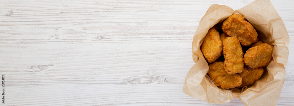 Chicken nuggets in a paper box over white wooden surface. Overhead, from above, flat lay. Space for text. Chicken nuggets in a paper box over white wooden surface. Overhead, from above, flat lay. Space for text.