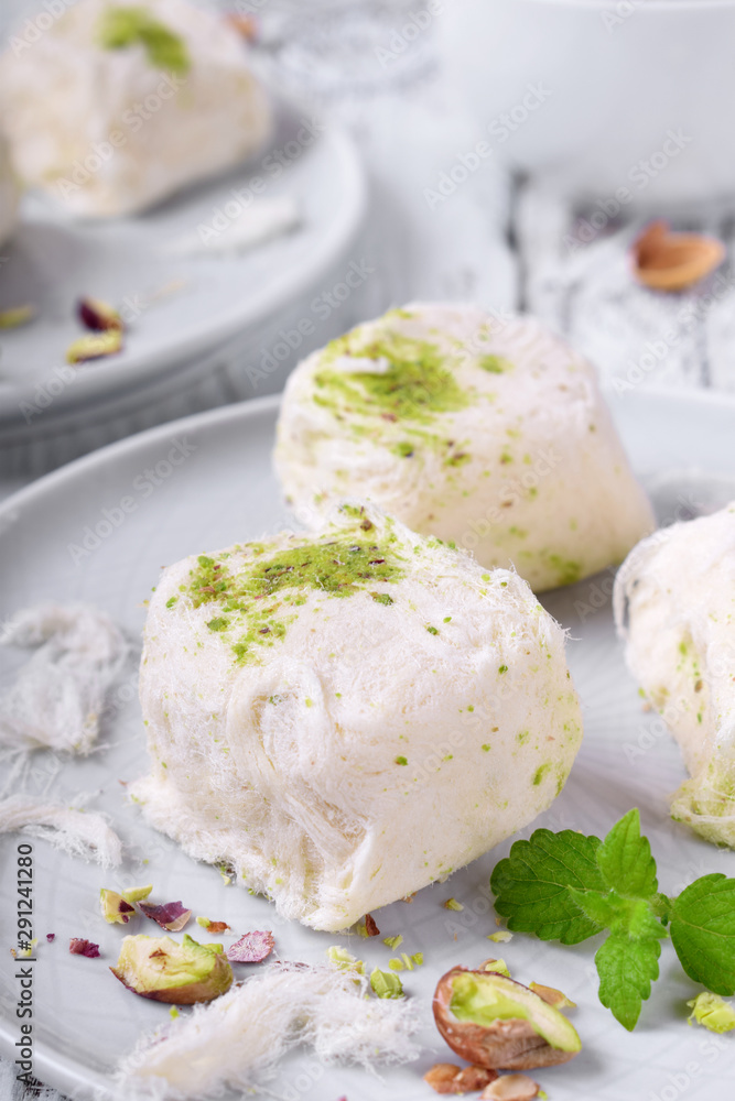 Cotton candy with pistachio on ceramic plate on white wooden table Cotton candy with pistachio on ceramic plate on white wooden table