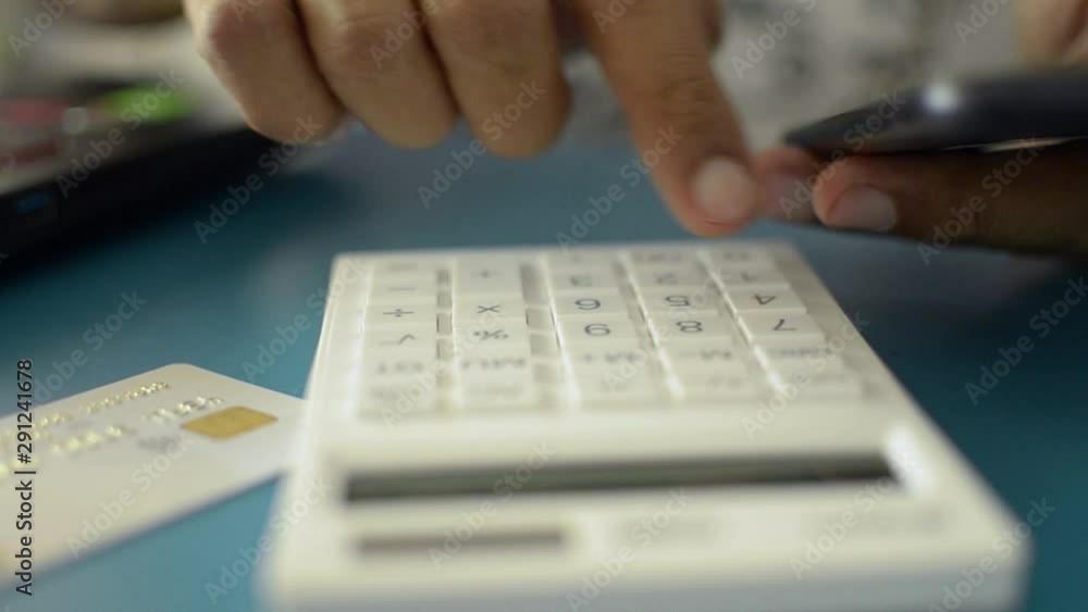 Hands of a man calculating expenses from credit card while using mobile phone data. Hands of a man calculating expenses from credit card while using mobile phone data.