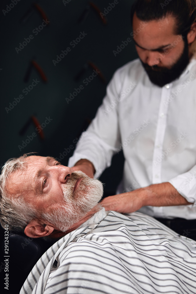 Obraz premium stylist covering senior man's body with a towel before making a new hairstyle. close up photo