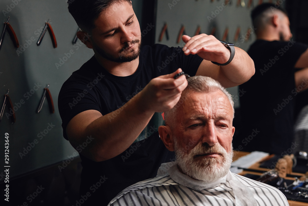 Fototapeta premium young man brushing old man's gray hair after cutting it. close up photo