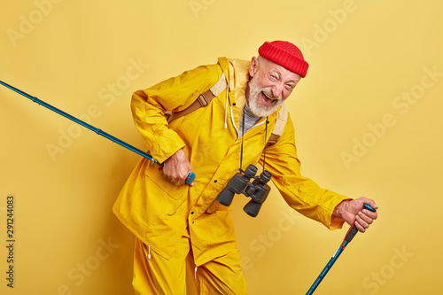 old crazy funny man walking with poles, lifestyle, close up photo. free time, spare time, isolated yellow bacakground, man keeps fit photo