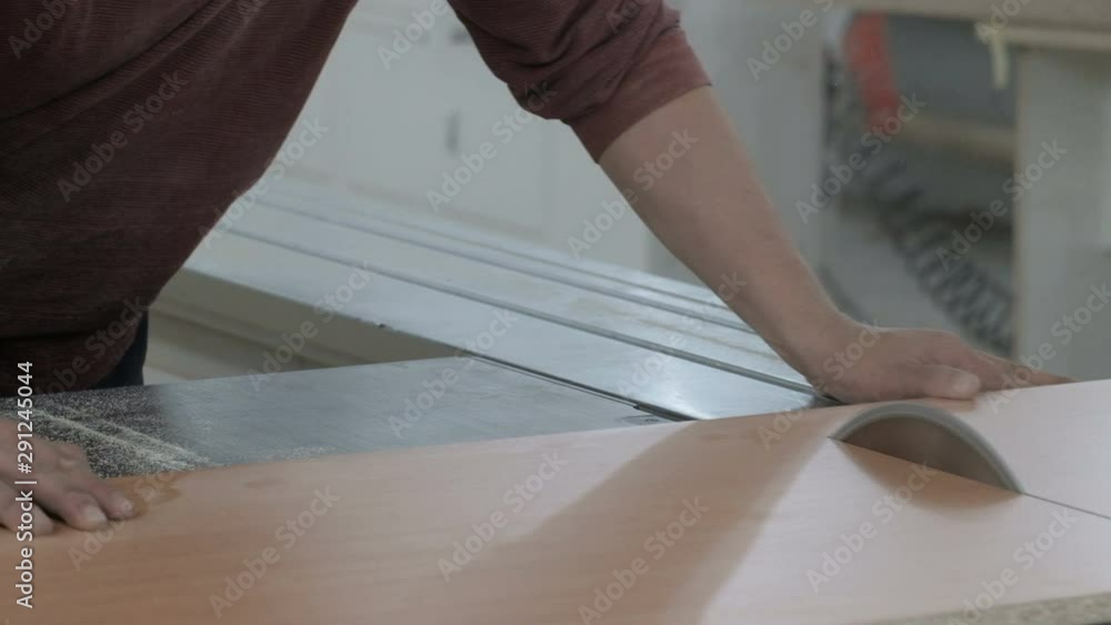 Woodworking machine with a circular saw. Furniture manufacture. Joiner saws a sheet of chipboard. Close-up.