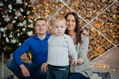 happy family with a child sitting at the Christmas tree on a blanket © Elena 