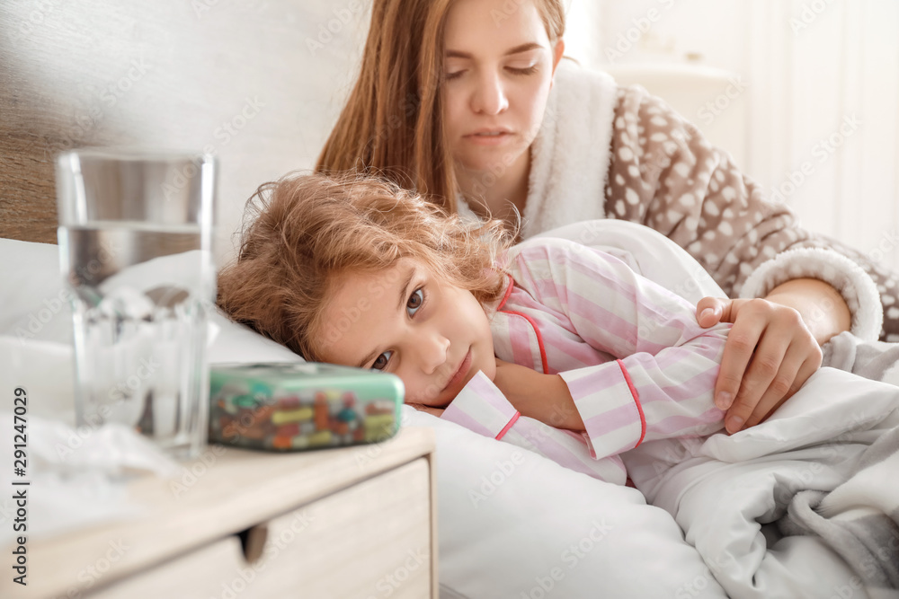 Mother taking care of her little daughter ill with flu at home Mother taking care of her little daughter ill with flu at home