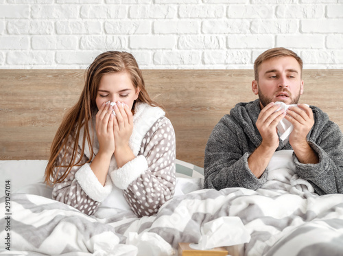 Sick young couple in bed at...