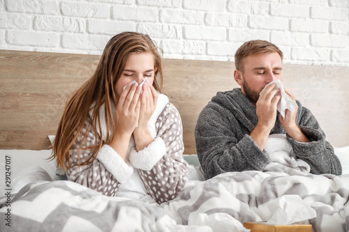 Sick young couple in bed at...