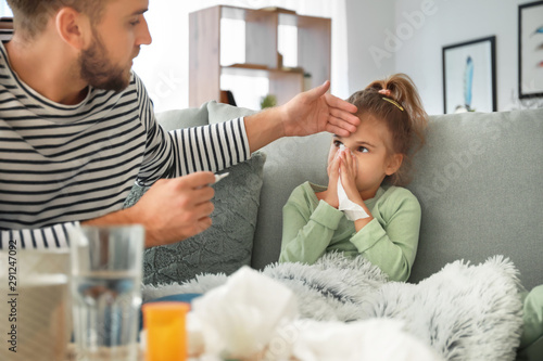 фотографія Father taking care of his daughter ill with flu at home