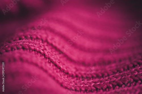 Knitted pink sweater with braid pattern close up. Winter season. Selective focus.