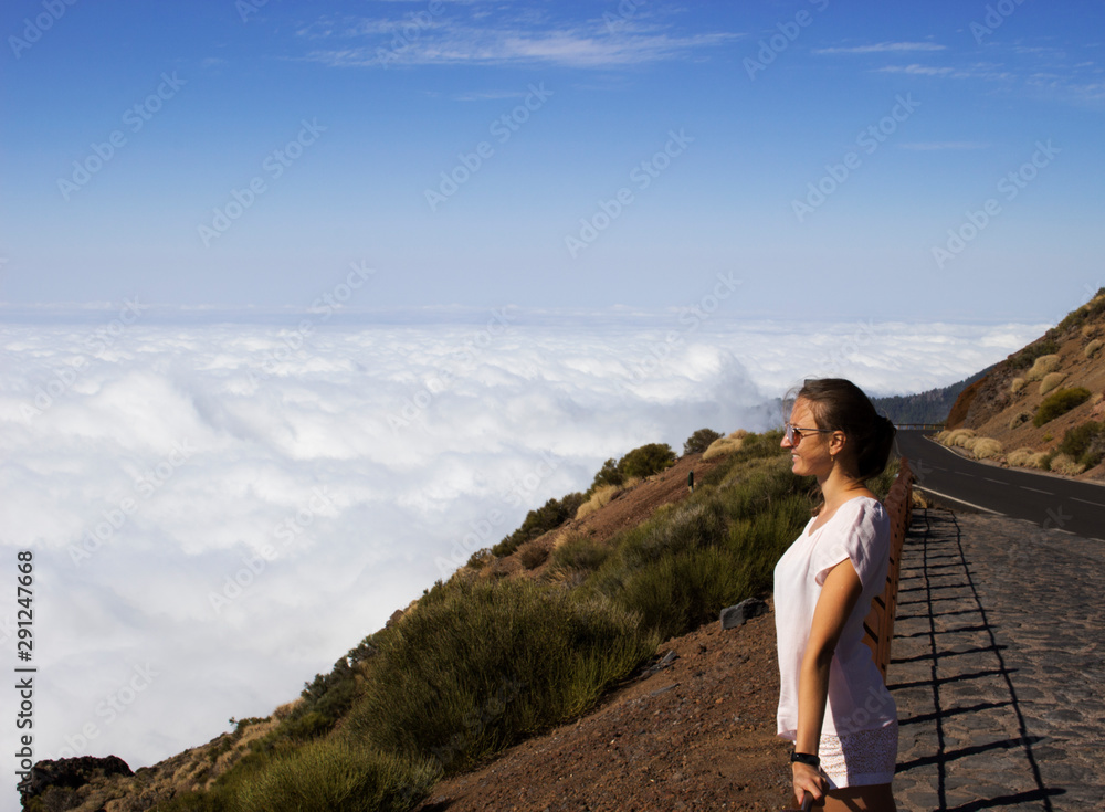 young woman on top of the mountain above the clouds