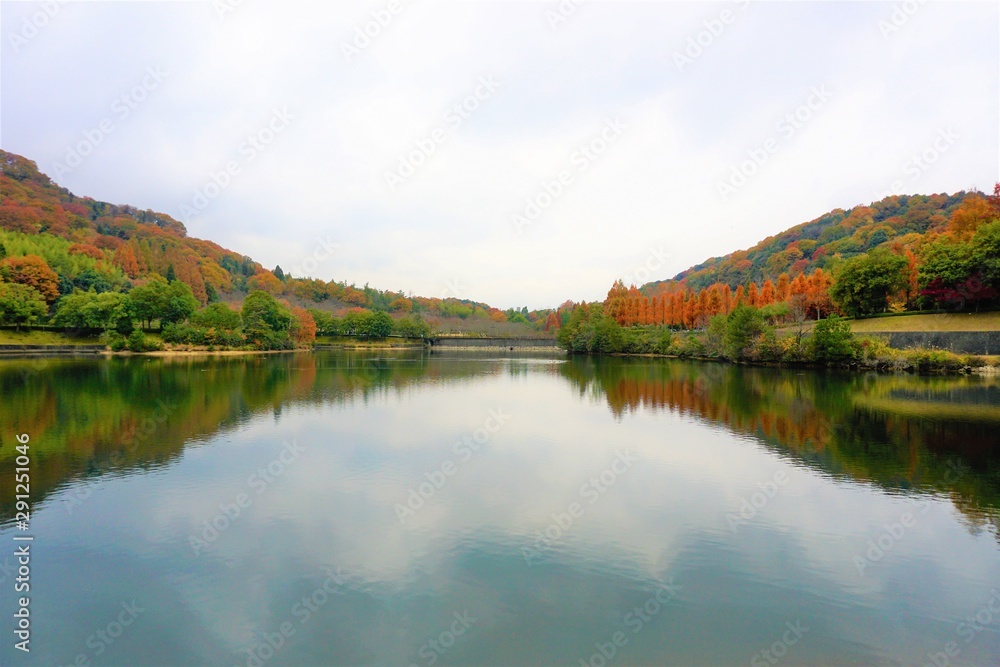ひょうたん島のような山を遠目に見つめながら、静かな大きな池の水面と、赤、橙、黄、黄土色、緑に色づいた紅葉を楽しむ