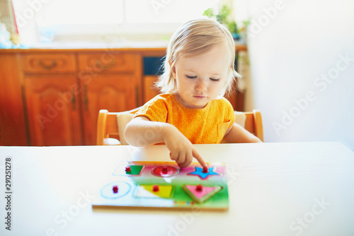 Adorable toddler girl doing wooden puzzle