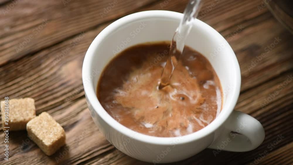 Hot water pouring into white cup with instant coffee. Closeup view wooden table background Hot water pouring into white cup with instant coffee. Closeup view wooden table background