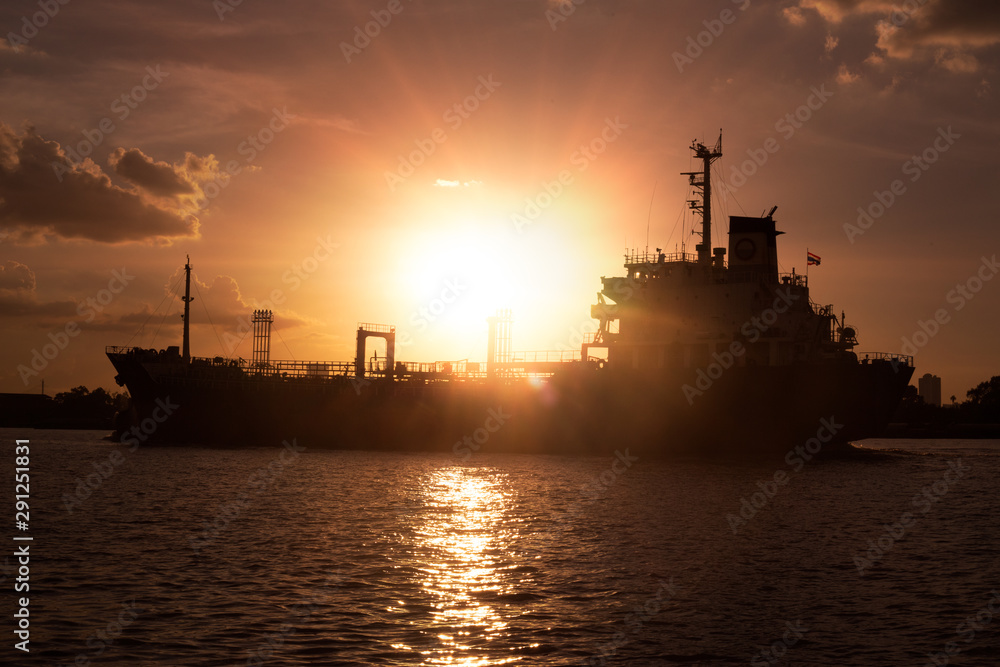 Logistics and transportation of International Container Cargo ship in the ocean at sunset,and silhouette of boat