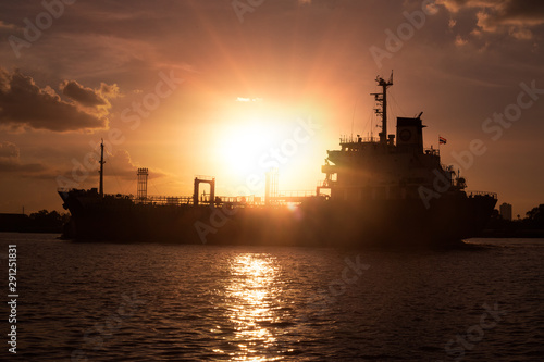 Logistics and transportation of International Container Cargo ship in the ocean at sunset,and silhouette of boat