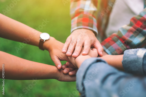 Closeup image of people putting their hands together in the outdoors