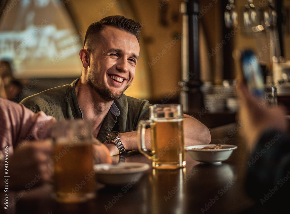 Cheerful friends drinking draft beer in a pub Cheerful friends drinking draft beer in a pub