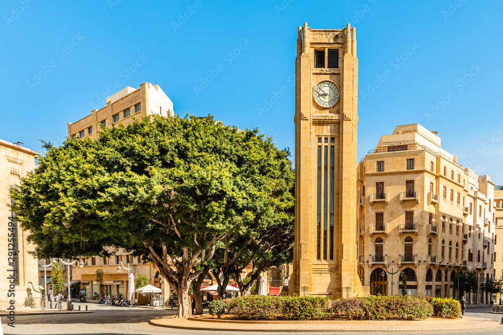 Obraz premium Wieża zegarowa na placu Al-Abed Nejmeh z drzewami i budynkami dookoła, Bejrut, Liban