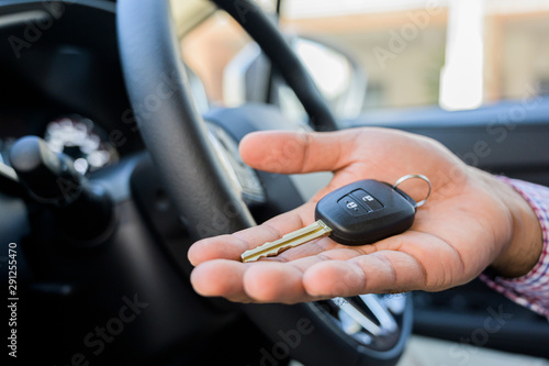Close up male hand showing car key while sitting in car.