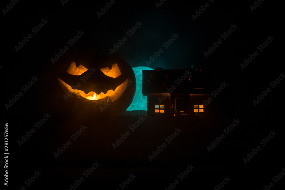 Fototapeta premium Horror view of Halloween pumpkin with scary smiling face. Head jack lantern with spooky building
