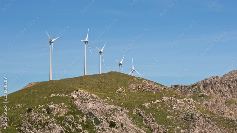Diagonal close-up shot of wind turbine farm in hill landscape on sunny day Diagonal close-up shot of wind turbine farm in hill landscape on sunny day