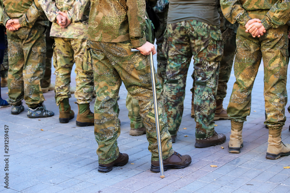 A wounded soldier of the Ukrainian army stands with a crutch near the formation of war veterans, Defender Ukraine Day. Armed forces of Ukraine, Ukrainian war A wounded soldier of the Ukrainian army stands with a crutch near the formation of war veterans, Defender Ukraine Day. Armed forces of Ukraine, Ukrainian war