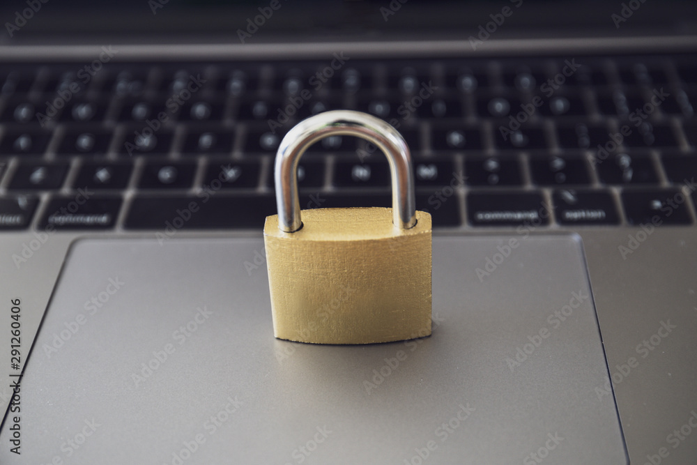 Computer security concept with a closed golden padlock on top of the keyboard Computer security concept with a closed golden padlock on top of the keyboard