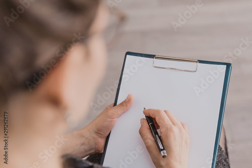 Photos the woman holds a pen and writes in a notebook