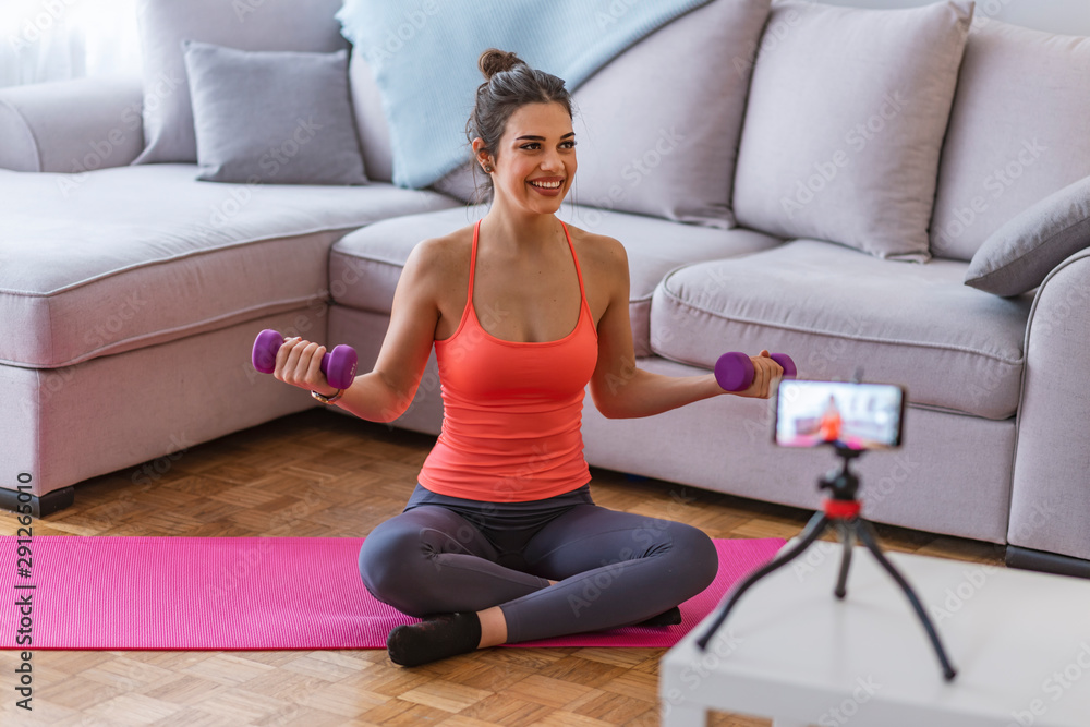 Young woman is exercising with dumbbells at home. Fitness, workout, healthy living and diet concept.