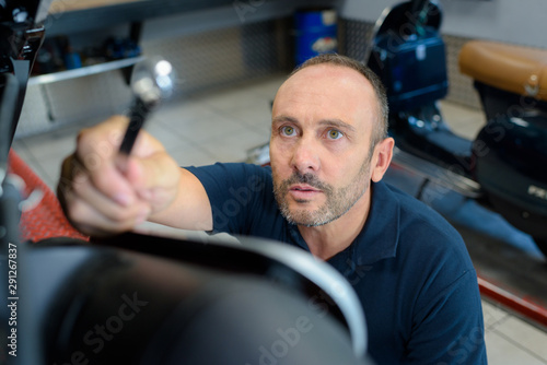 mechanic reaching up for tool