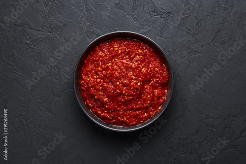 Schezwan Sauce in black bowl at dark background. Schezwan Sauce is Indo-chinese or Sichuan cuisine hot sauce with red chilli, garlic and ginger. photo