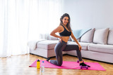 Young happy fitness girl with sporty body wearing sportswear smiling at the camera while sitting on the yoga mat. Sport healthy concept. Portrait of young attractive woman doing exercises.