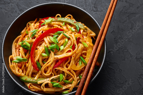 Vegetarian Schezwan Noodles or Vegetable Hakka Noodles or Chow Mein in black bowl at dark background. Schezwan Noodles is indo-chinese cuisine hot dish with udon noodles, vegetables and chilli sauce