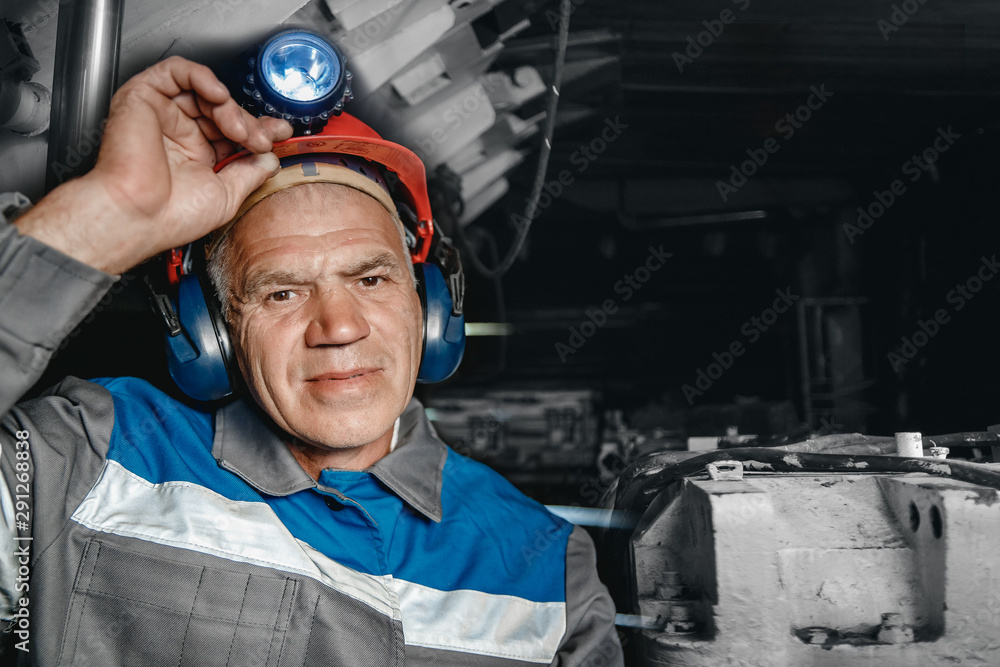 Portrait miner coal man in helmet with lantern in underground mine. Concept industrial engineer Portrait miner coal man in helmet with lantern in underground mine. Concept industrial engineer