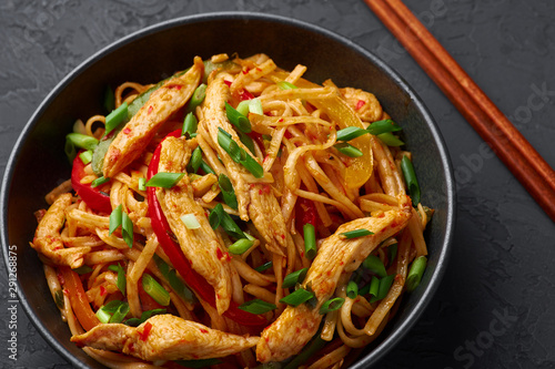 Chicken Schezwan Noodles or Hakka or Chow Mein in black bowl at dark background. Schezwan Noodles is indo-chinese cuisine hot dish with udon noodles, vegetables and chilli sauce or Schezwan sauce