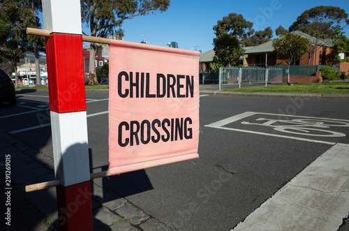 Flag of ‘Children Crossing’ on suburban street. Melbourne, VIC Australia. When displayed, drivers must not proceed through the crossing if children are still on the crossing or about to start crossing